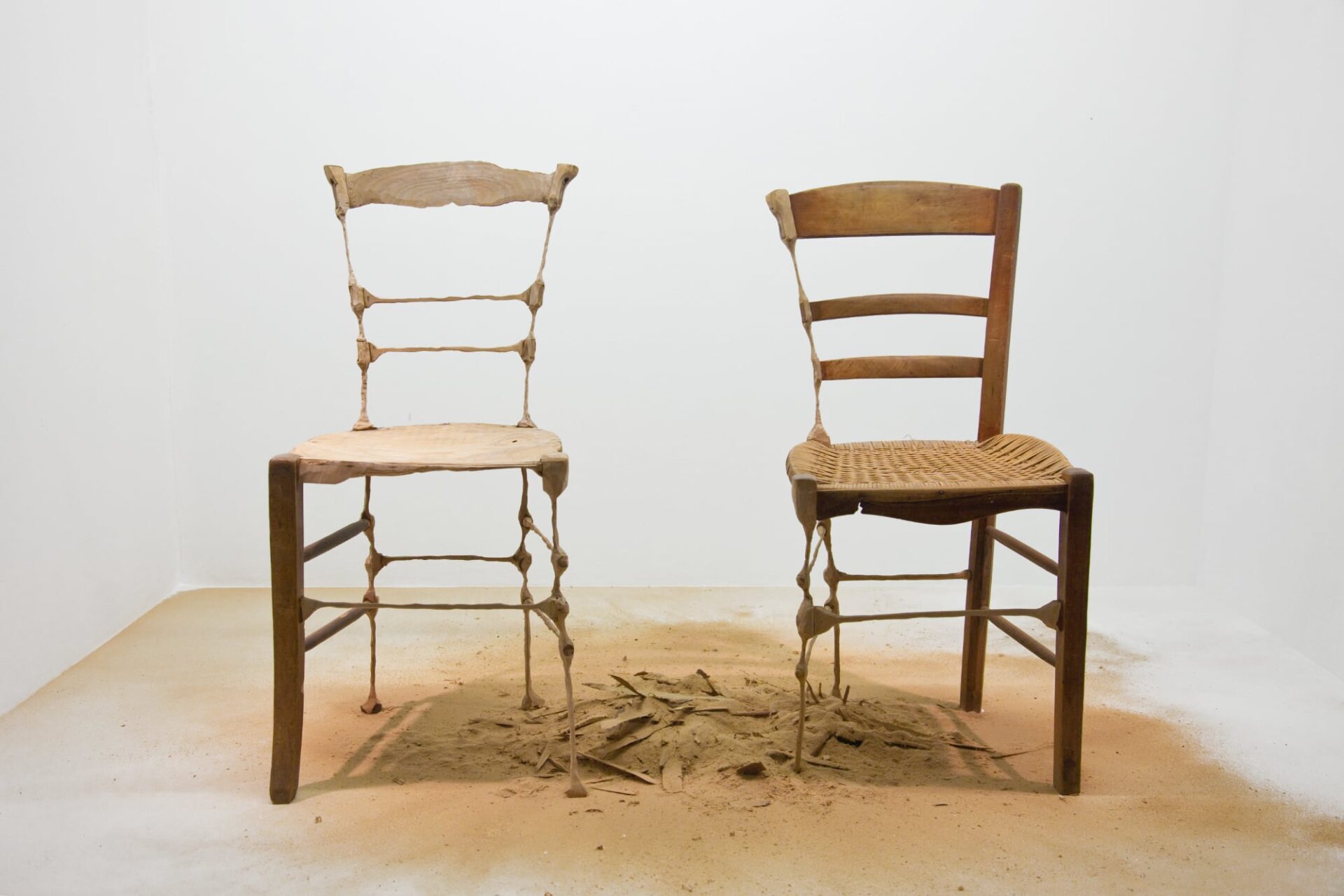 two wooden chairs sitting side by side with their inner leg sawed down to spindly bits