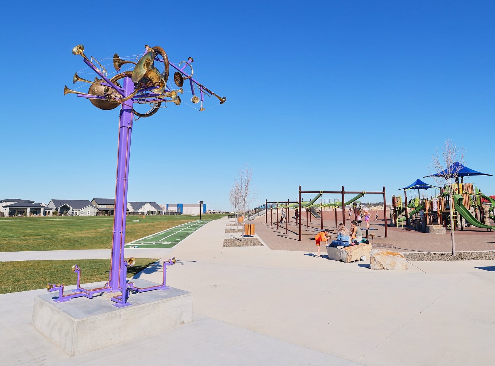 a cluster of brass instruments atop a purple pole near a playground