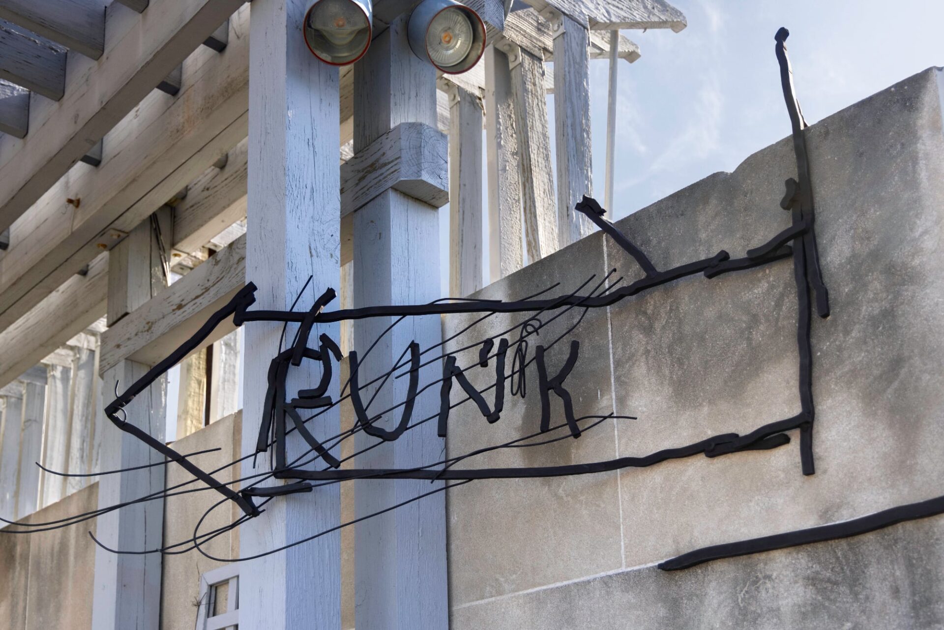 a scratchy wall sculptures of an arrow with the words runk on a roof that appears as if it were hand drawn