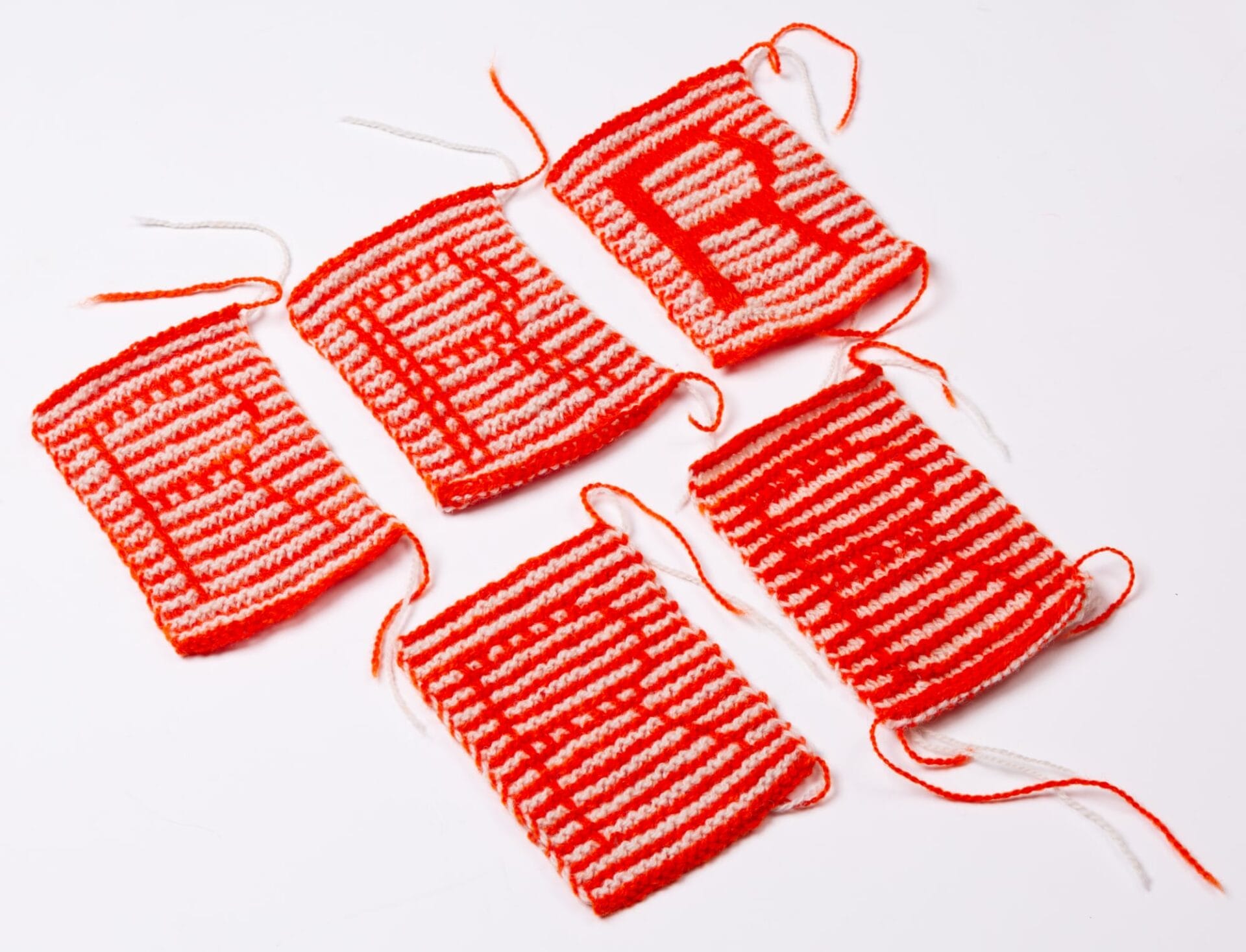 five orange and white striped knitted squares with the letter r written in them