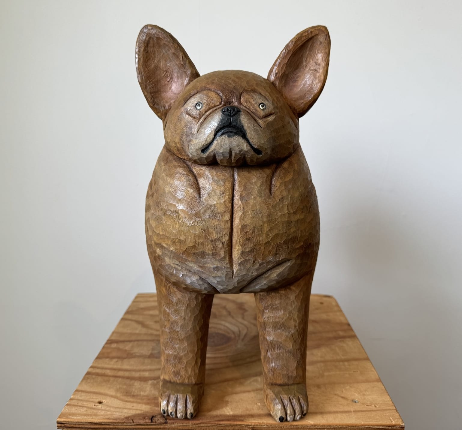 a wooden sculpture of a brown French bulldog