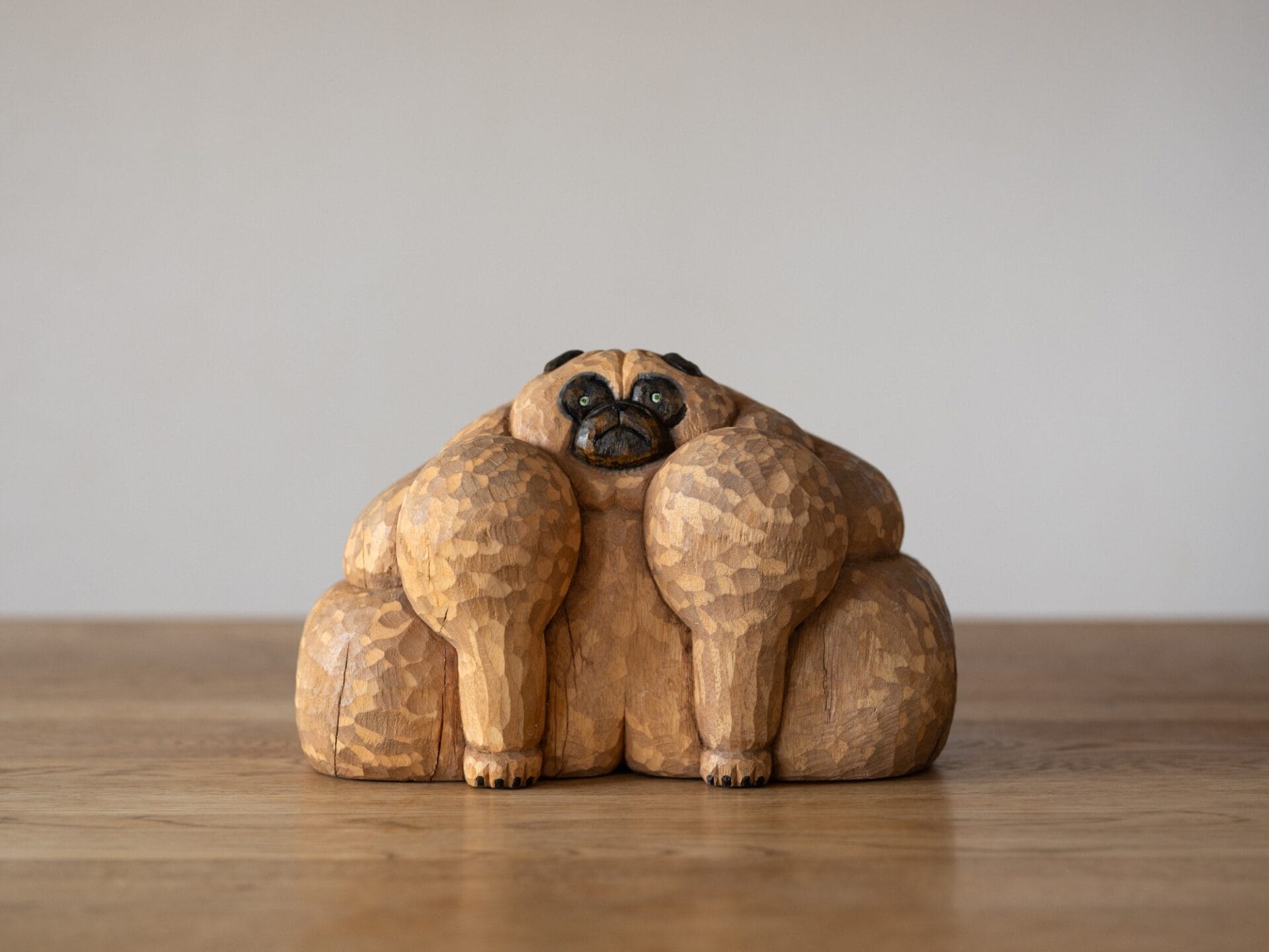 a whimsical wooden sculpture of a pug with large, bulky muscles