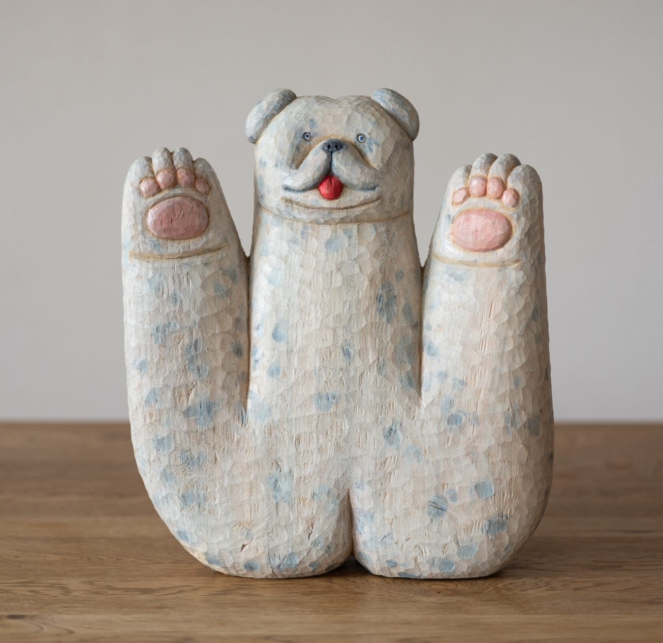 a wooden sculpture of an abstracted white dog with large paws