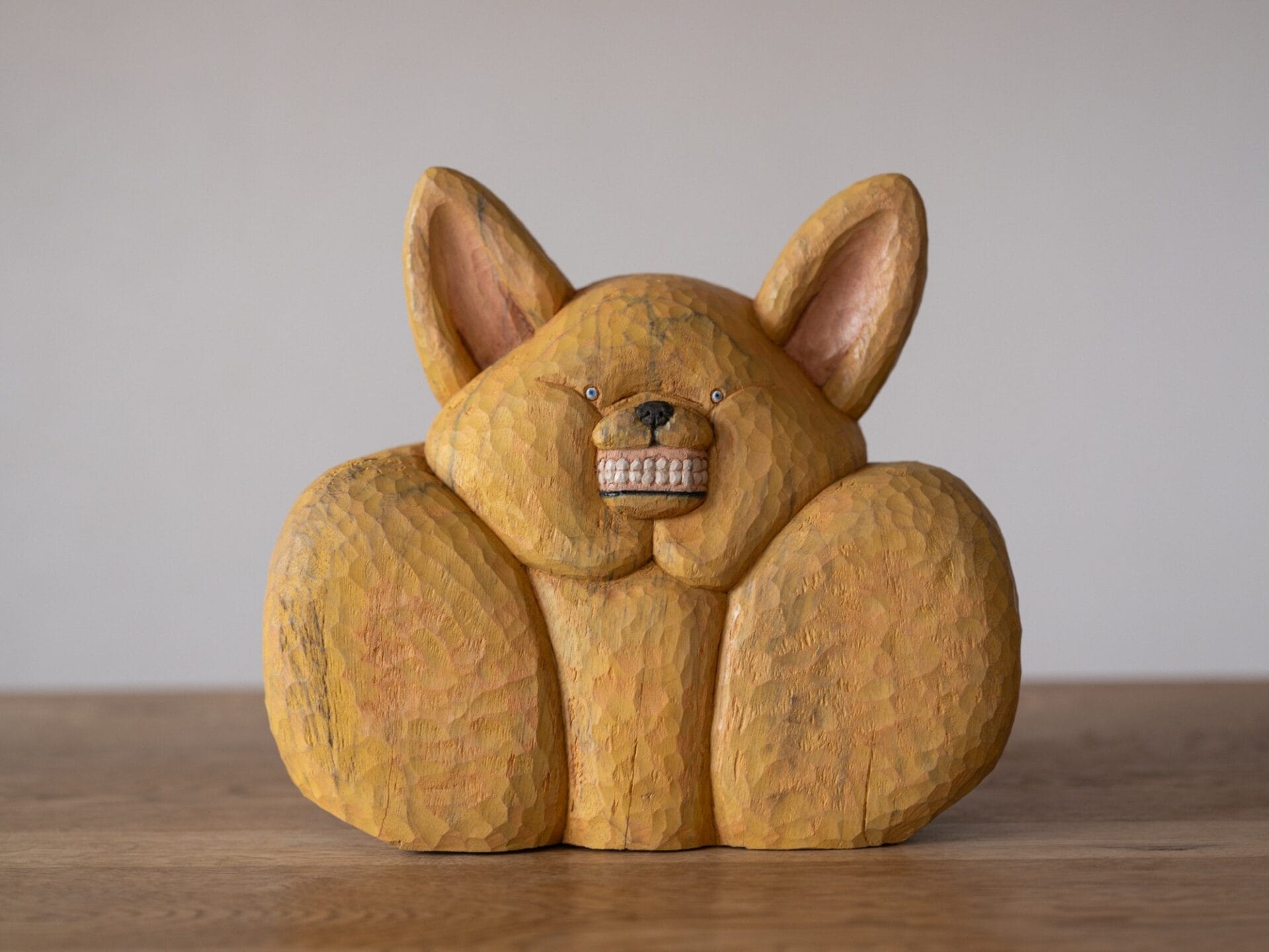 a playful wooden sculpture of a chihuahua-type dog baring its teeth