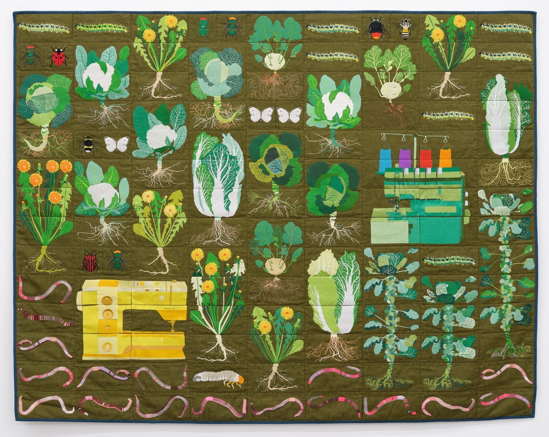 a green quilt with an array of lettuces, insects, worms, sewing machines, and other creatures.