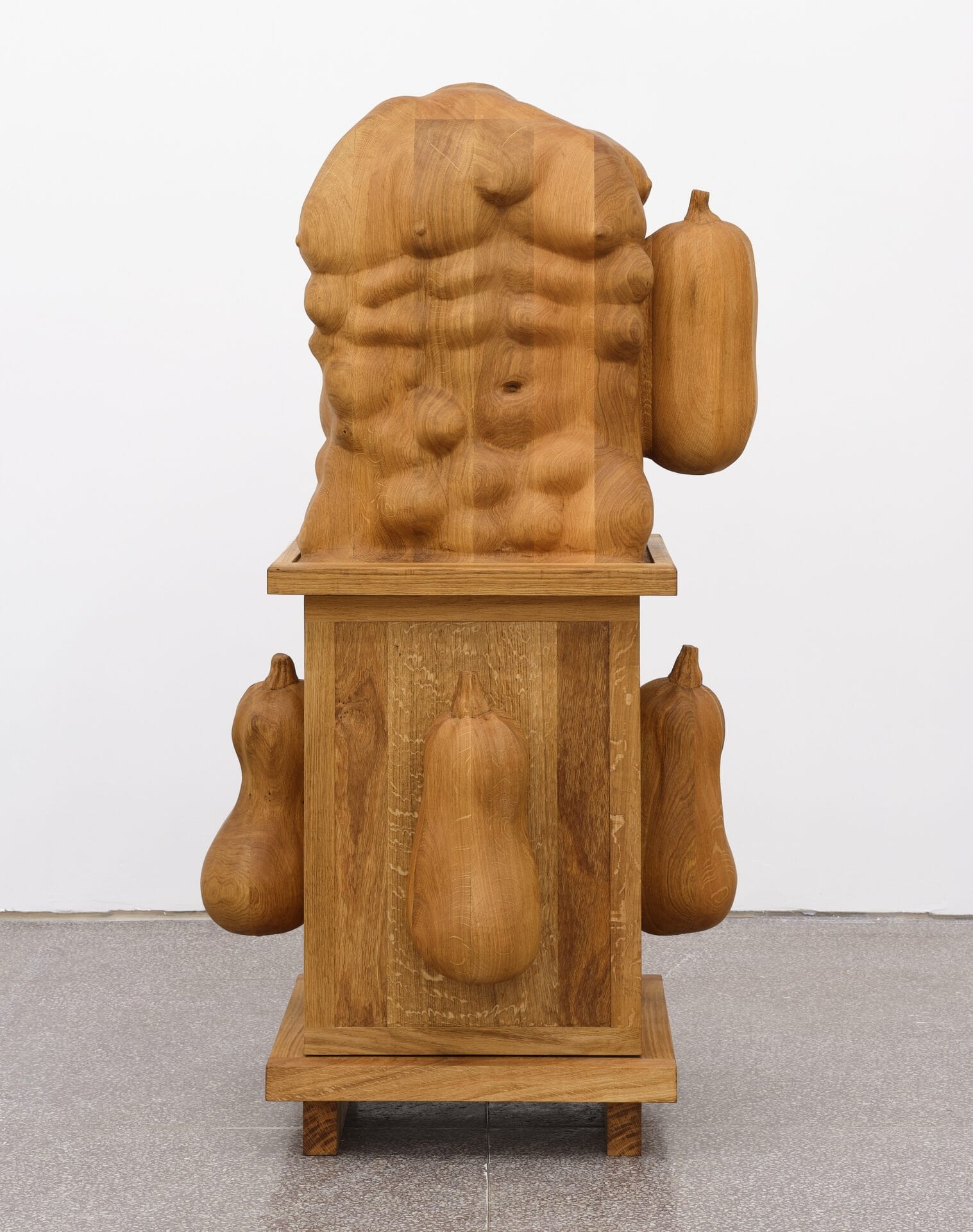 an oak cabinet with eggplants and an abstracted human torso on top