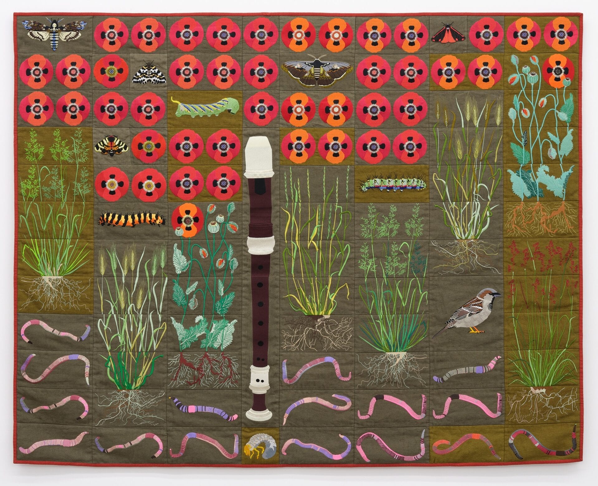 a green quilt with a pattern of flowers, worms, plants, insects, and a clarinet