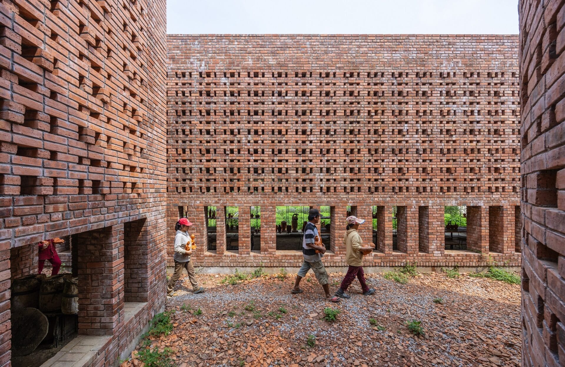 people walk through the courtyard of a contemporary brick building