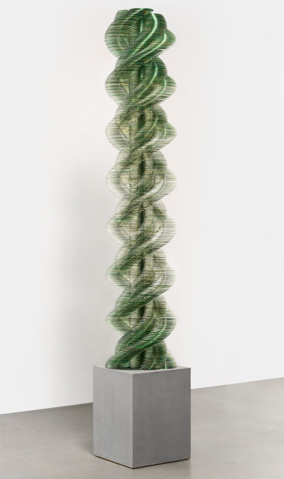 a twisting green sculpture on a concrete pedestal