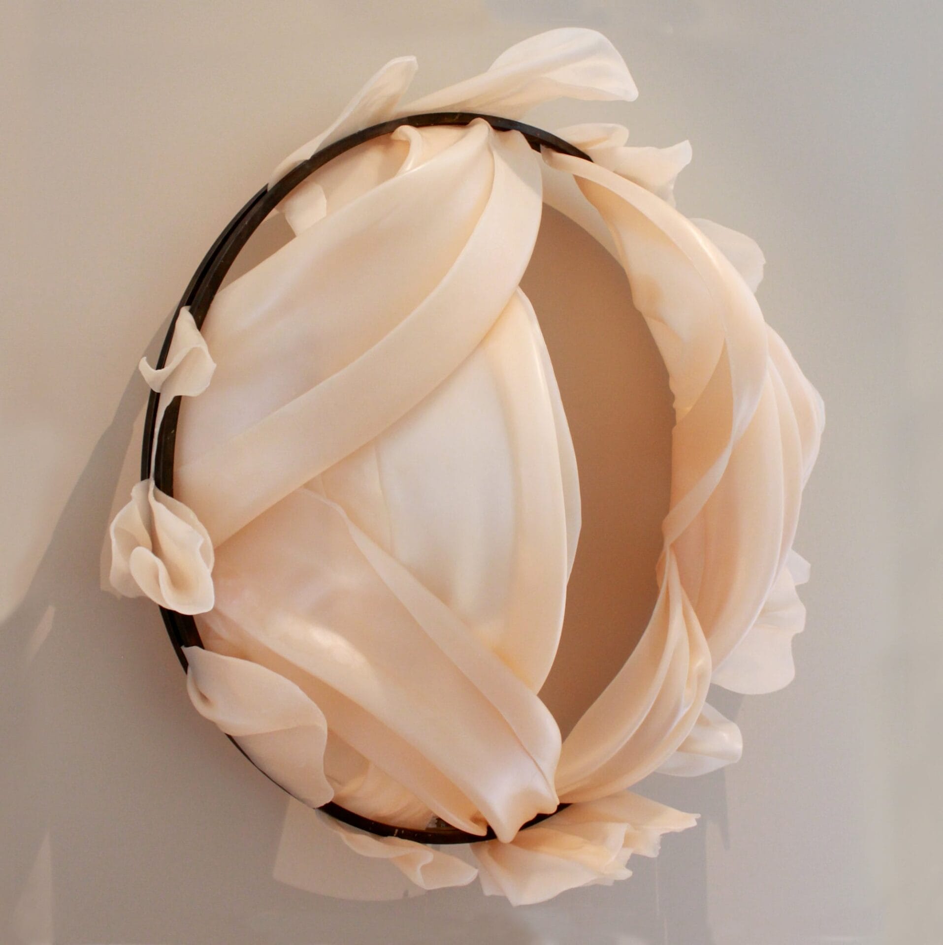 a circular wall sculpture with thin wax sheets billowing out around it