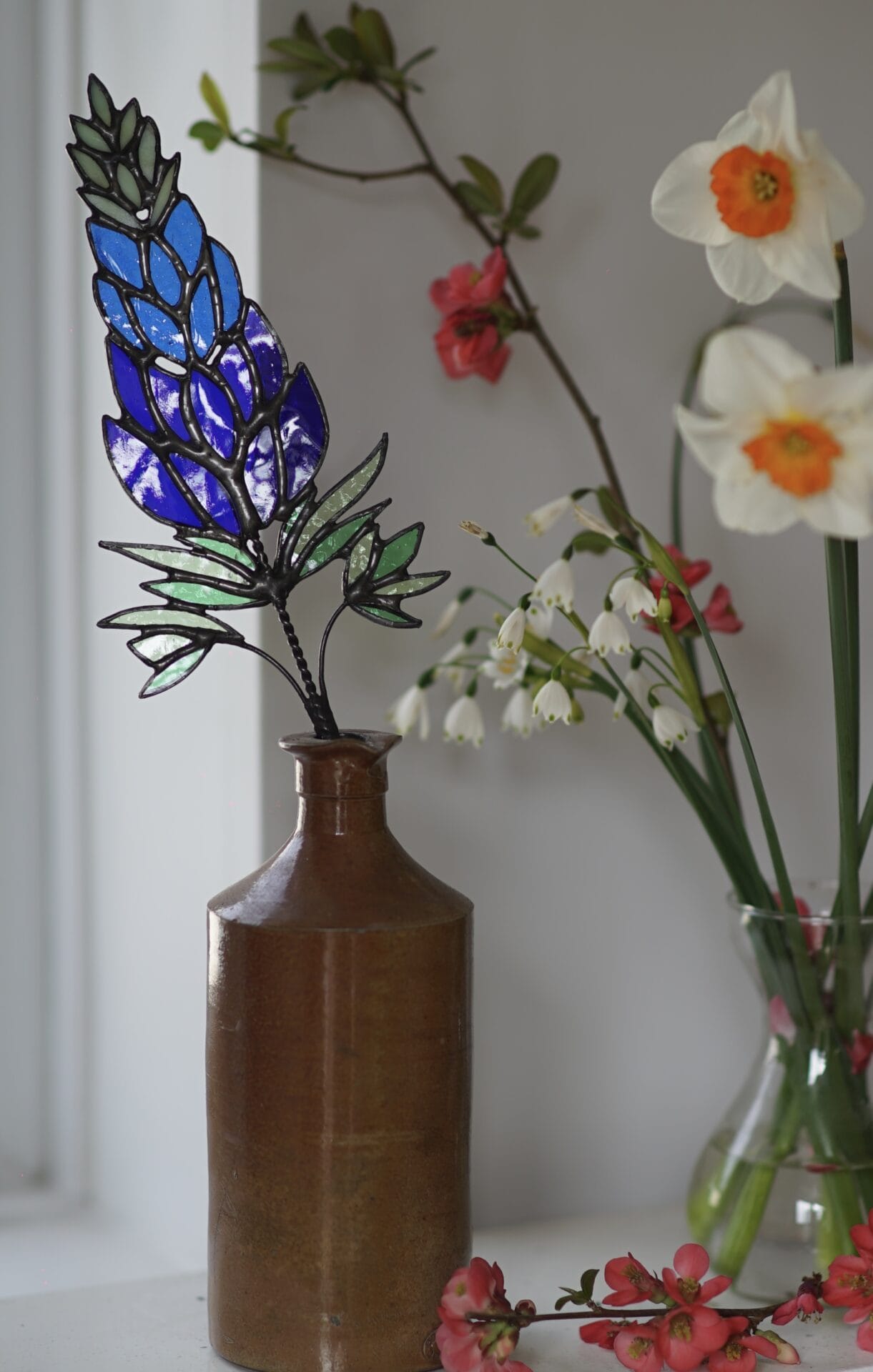 stained glass flowers and vines in ceramic vases alongside live specimens
