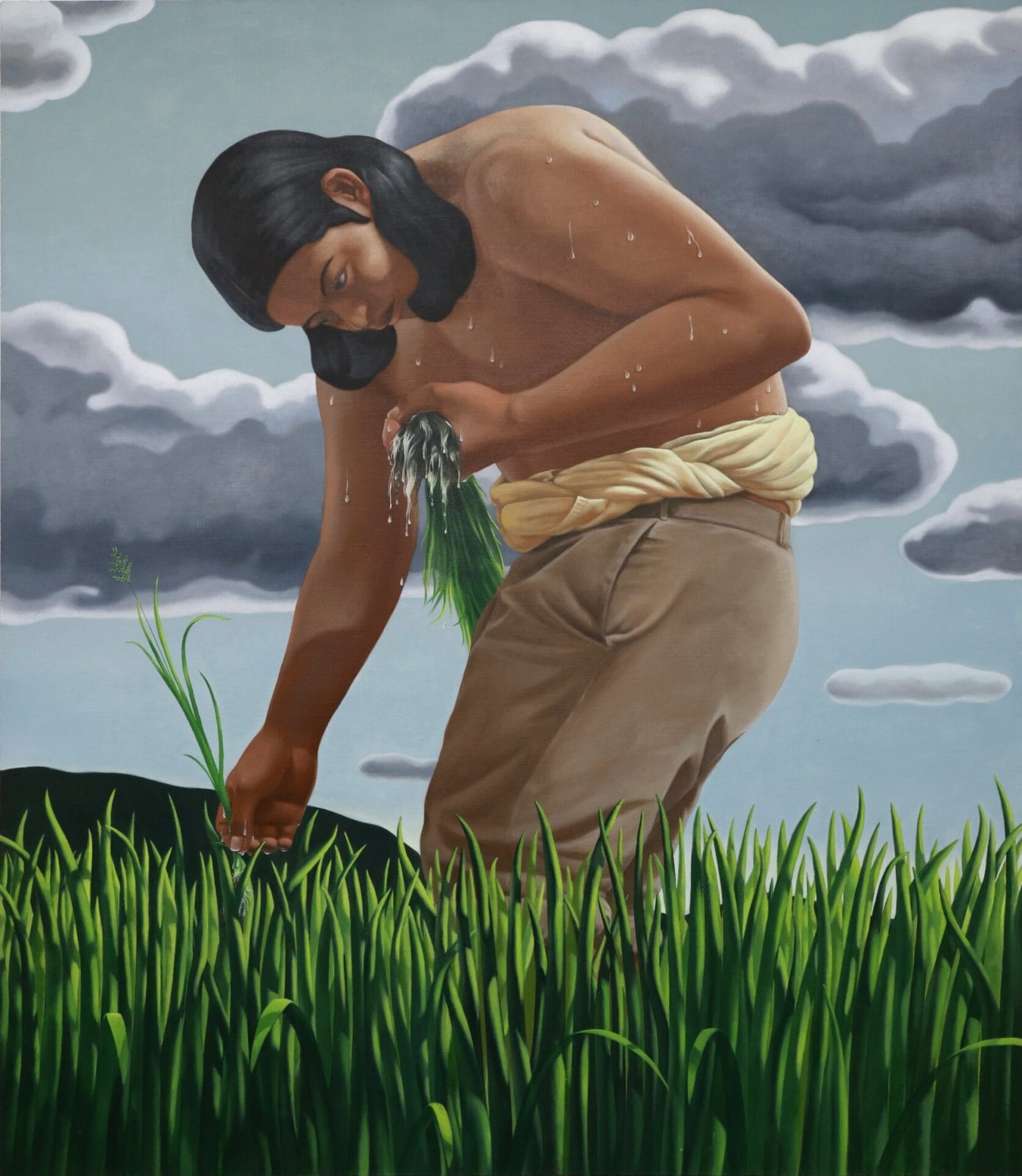 a shirtless man hunches over and grasps green grass in a field