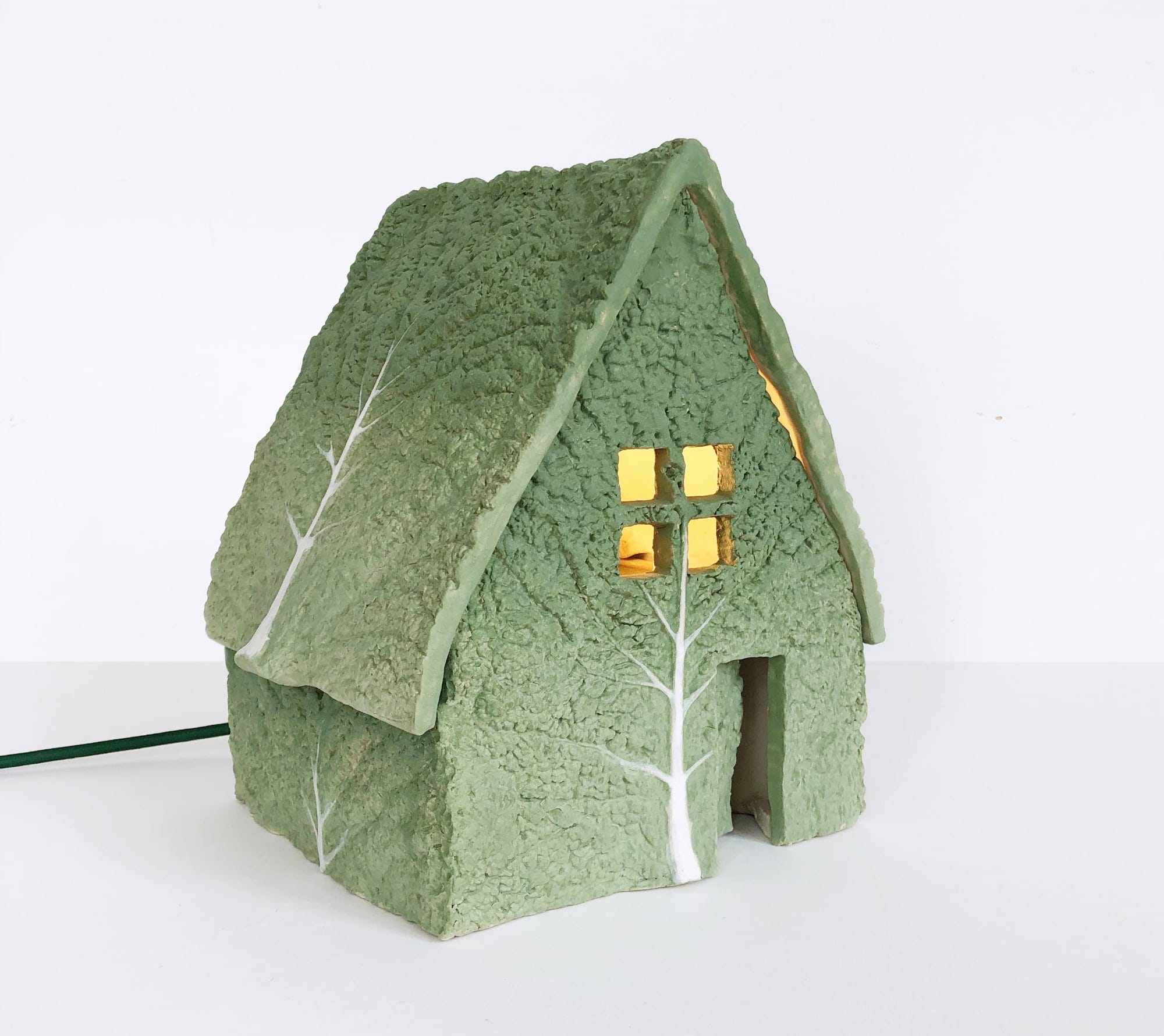 ceramic green cabbage leaves form a house structure with a light inside