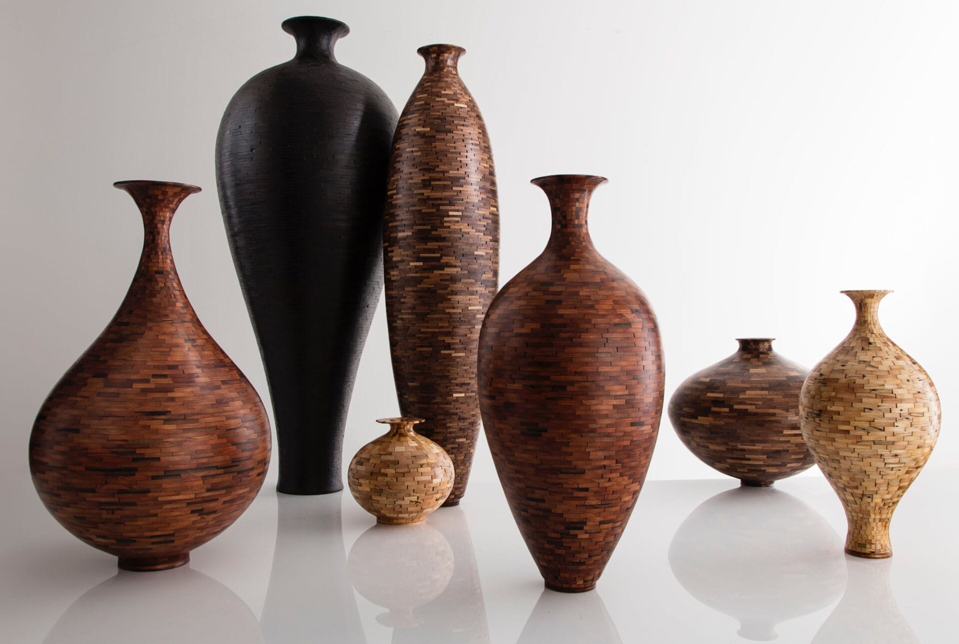seven curvy wooden vessels made of wood components fitted together