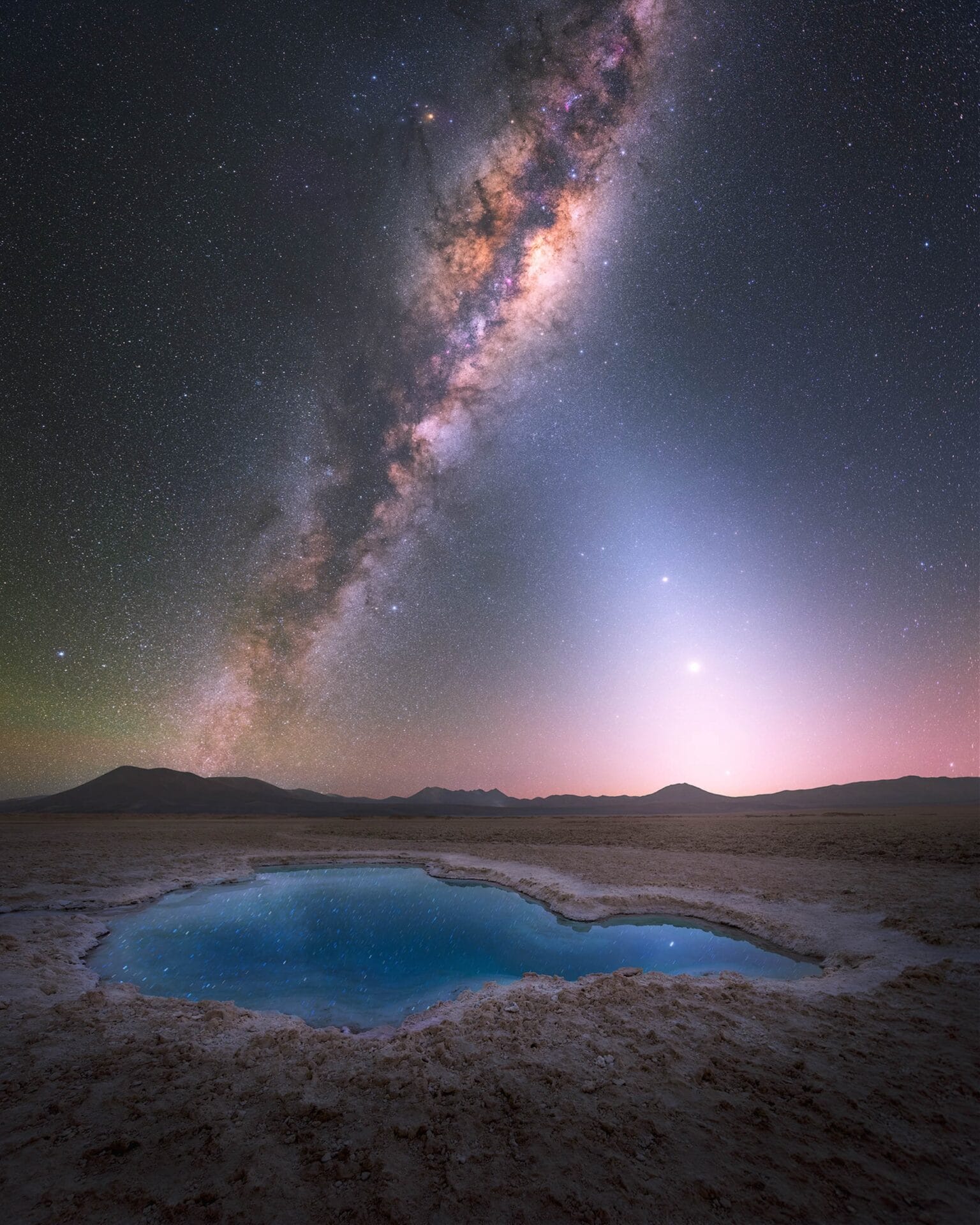 the brilliant star studded milky way above a lake with mountains in the background