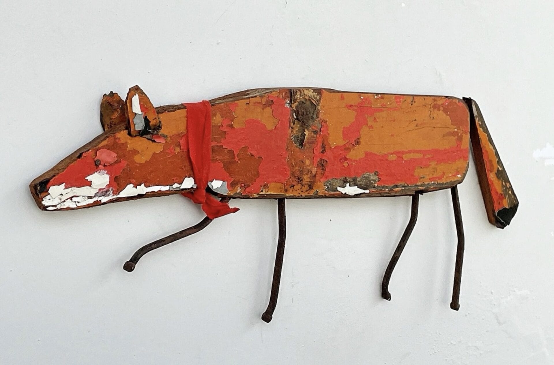 a fox sculpture made from repurposed, painted wood with rusty nails for legs