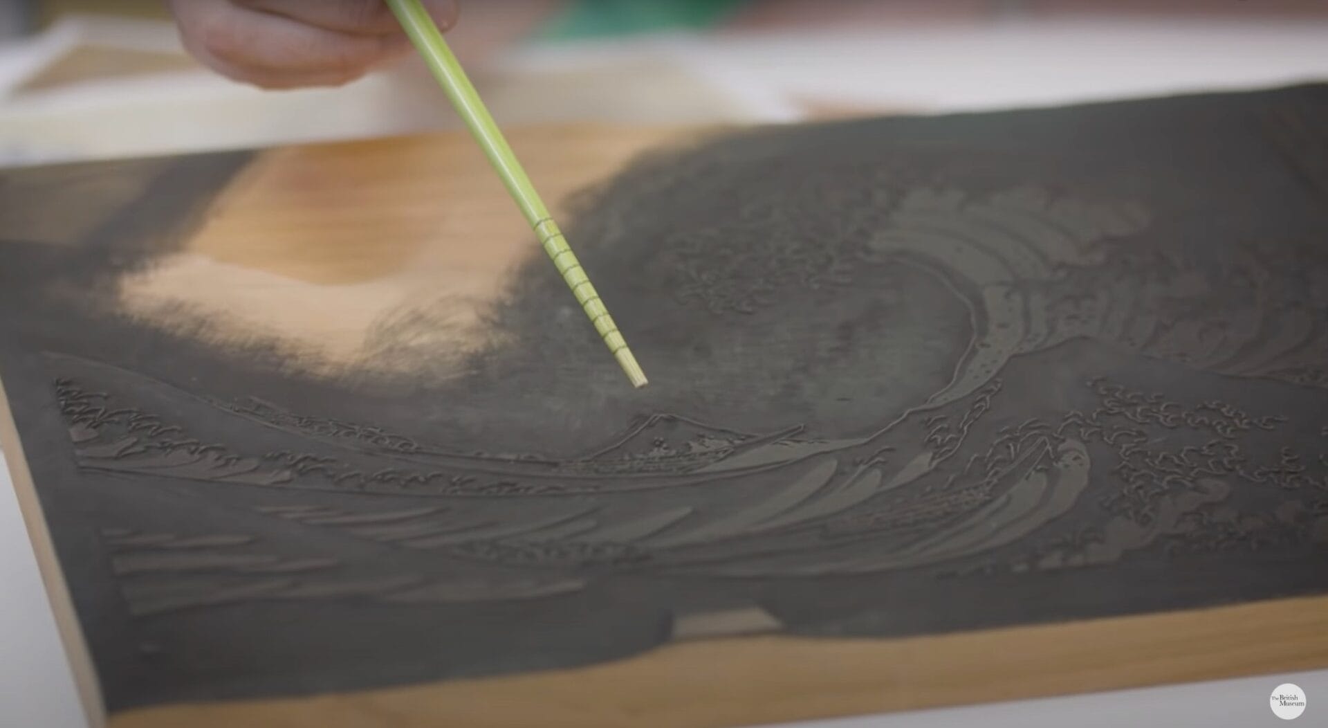 a still from a short documentary about Hokusai's "The Great Wave" print, showing a detail of a reproduced woodblock