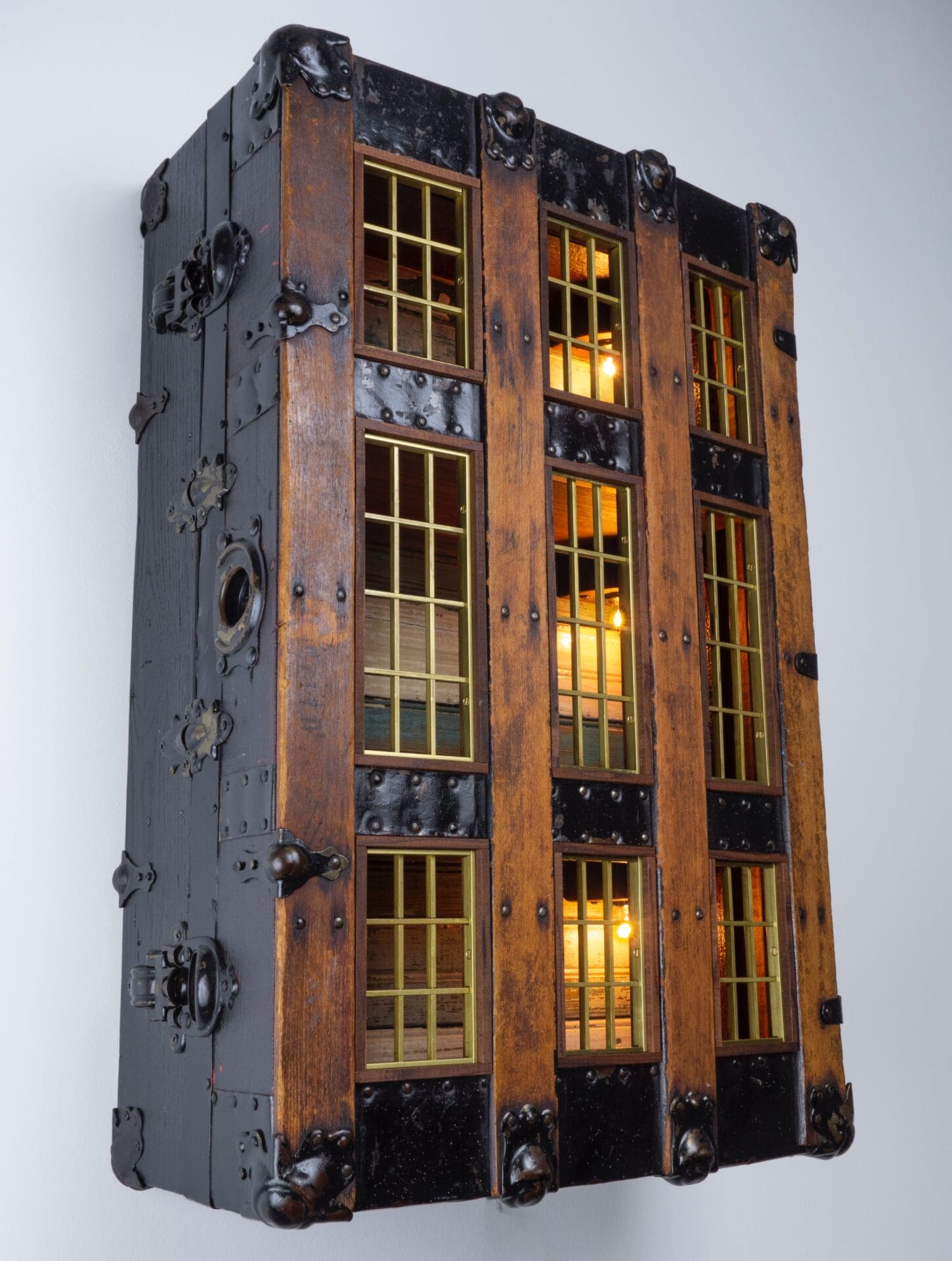 a wooden trunk standing upright with wooden windows carved from the top and lights inside