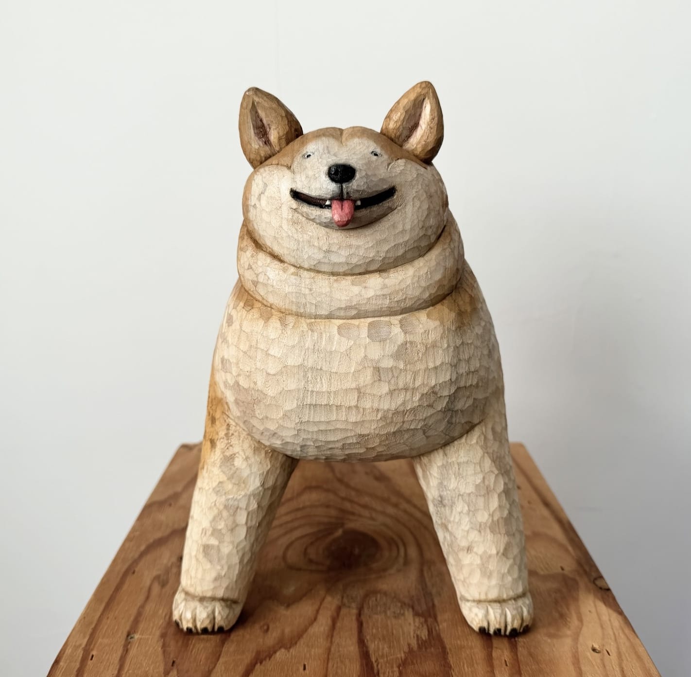 a playful shiba inu dog carved out of wood