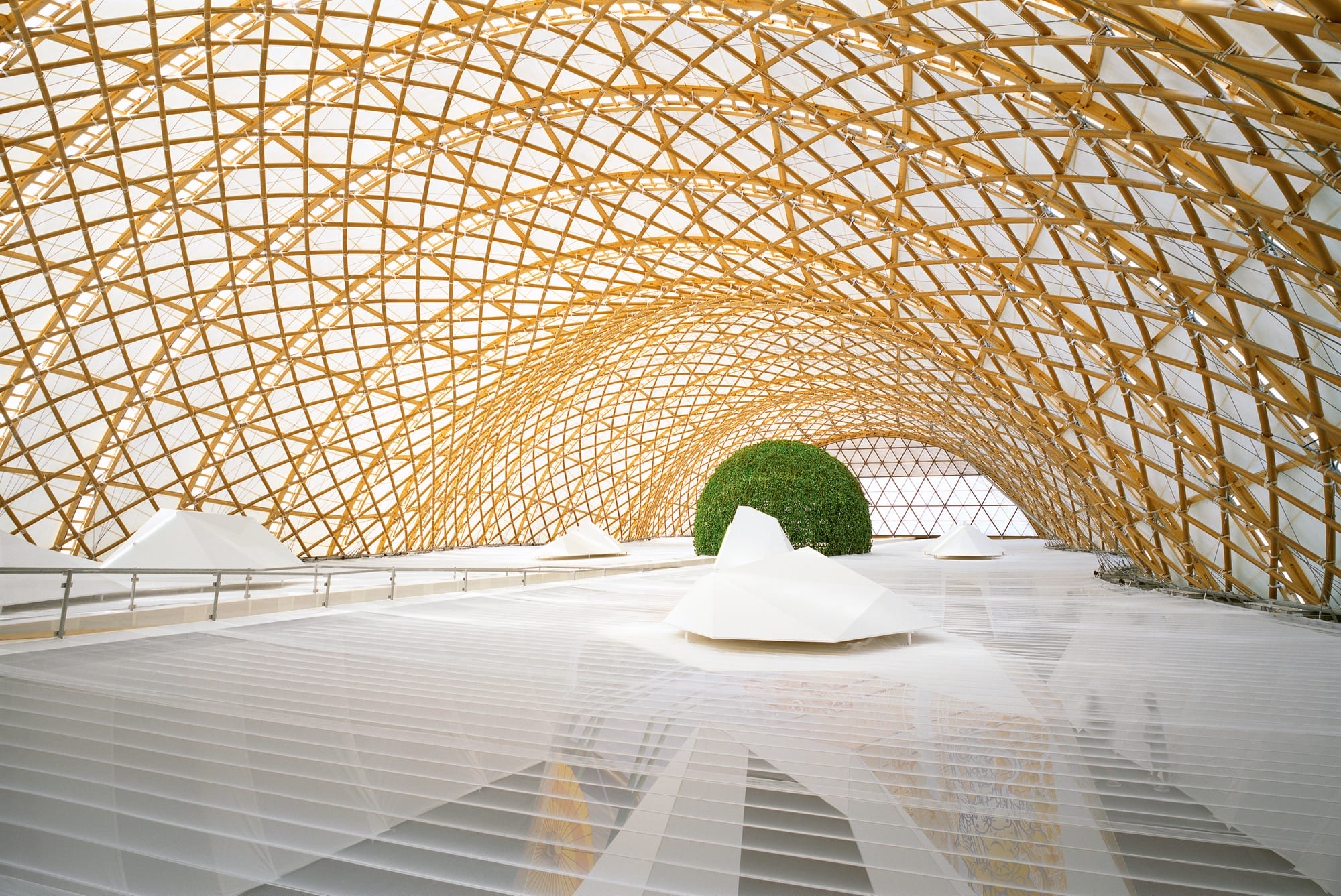 the interior of the Japan Pavilion at Expo 2000 in Hanover, showing a long, arched interior with white floors and a ceiling of latticework