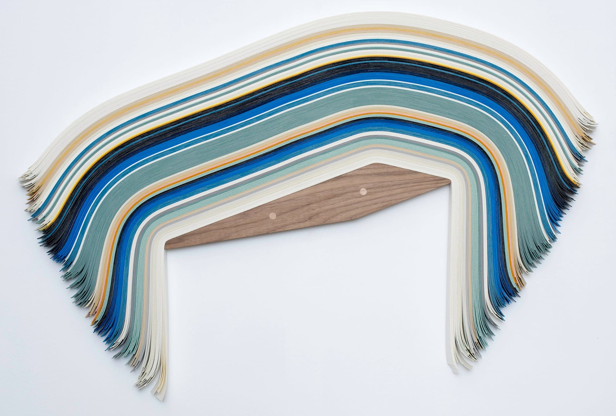 blue, gray, tan, and beige vinyl strips slump in a striped pattern across a wooden triangle