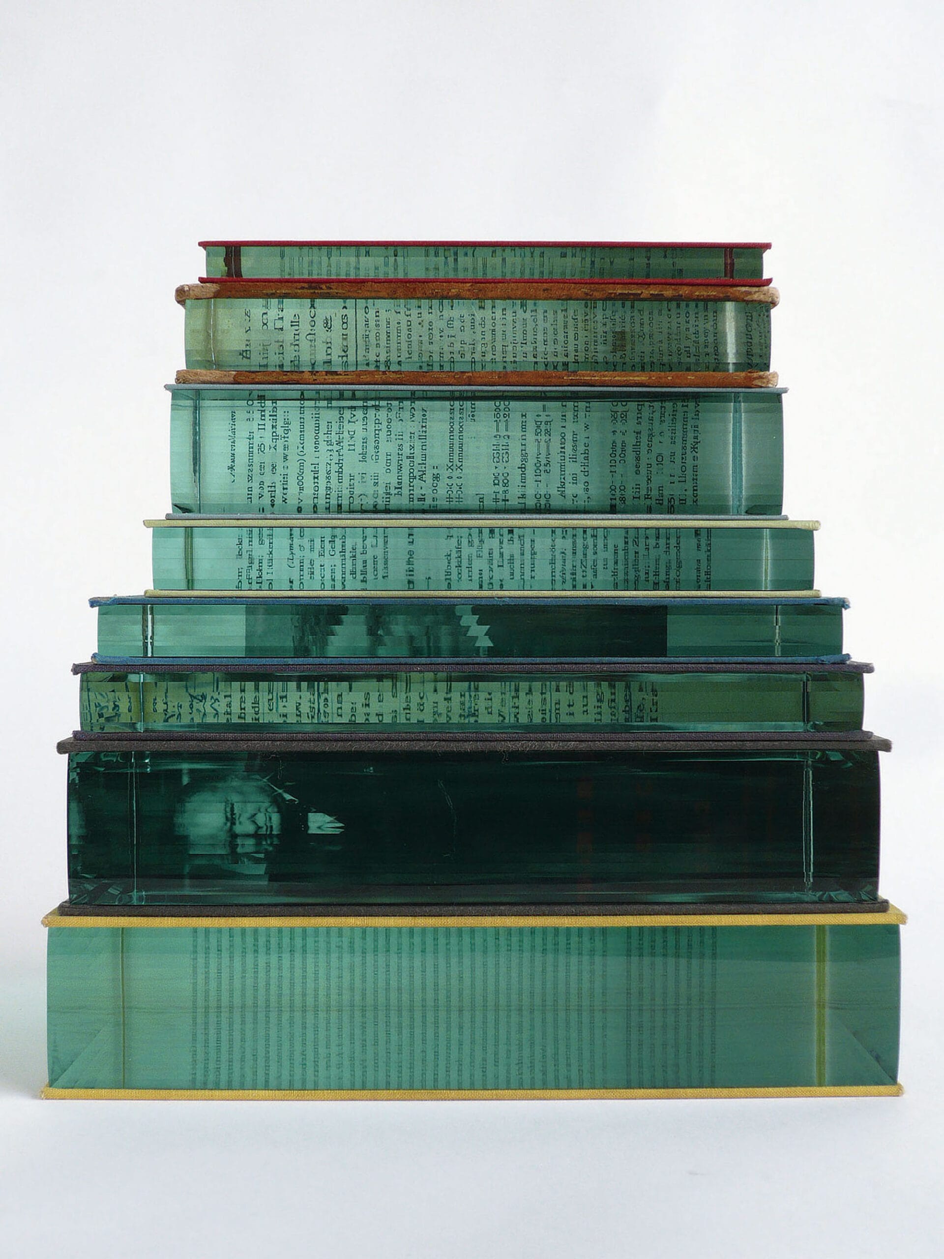 a stack of seven books, its pages replaces with an embedded section of layered of aquamarine glass