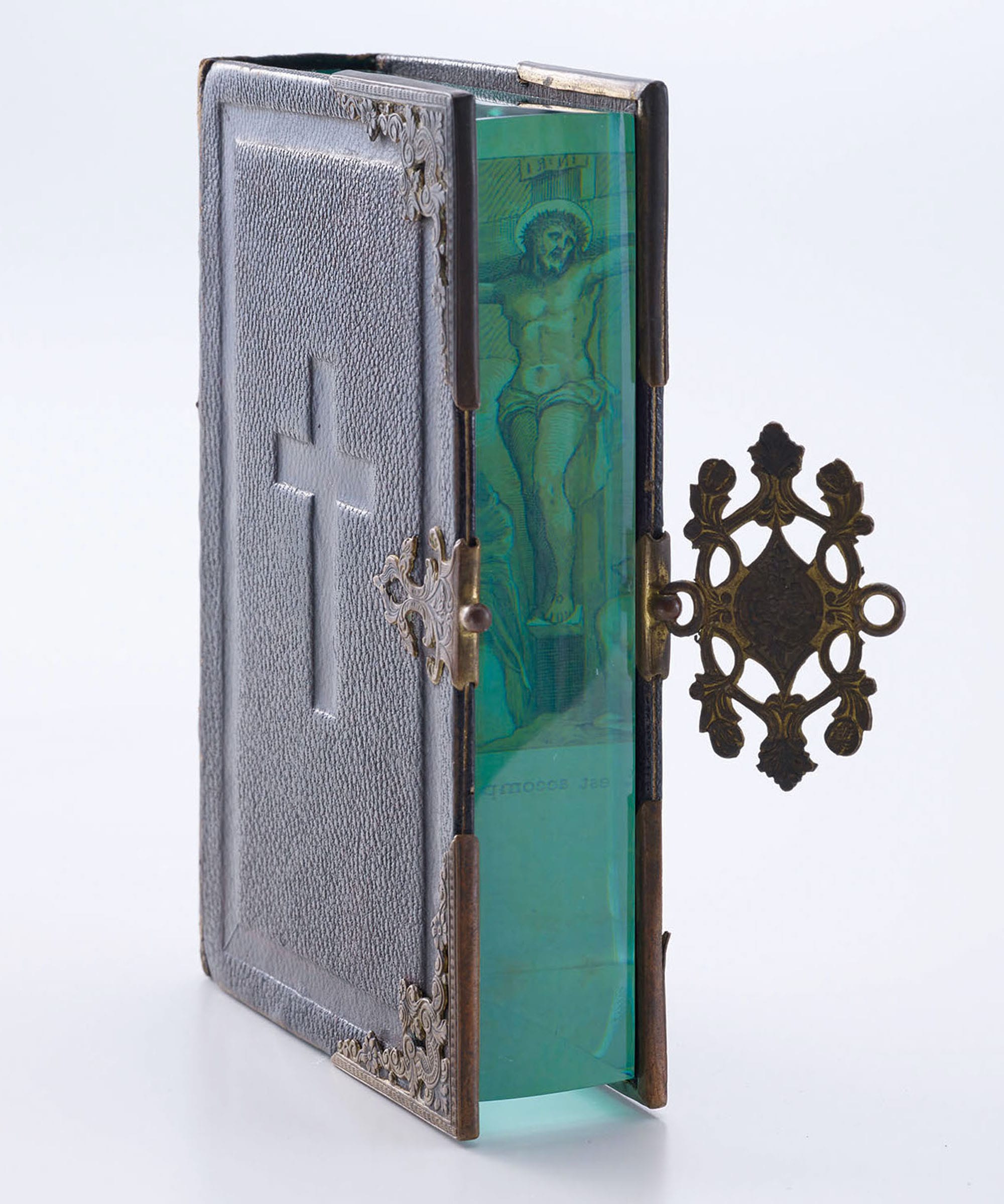 a book with a cross on the cover including an embedded section of layered of aquamarine glass