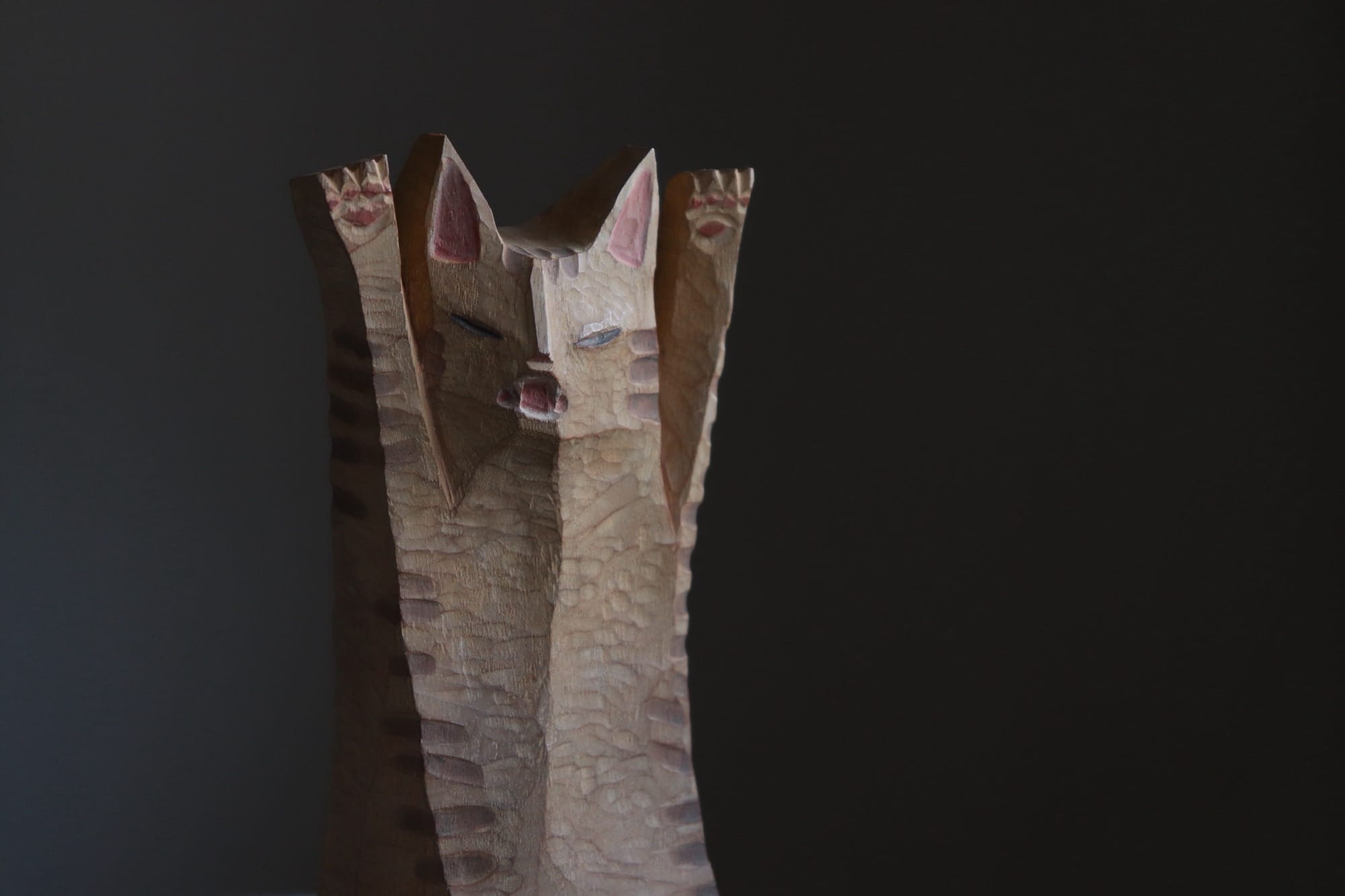 a wooden sculpture of a cartoonish cat, hissing and raising its front paws