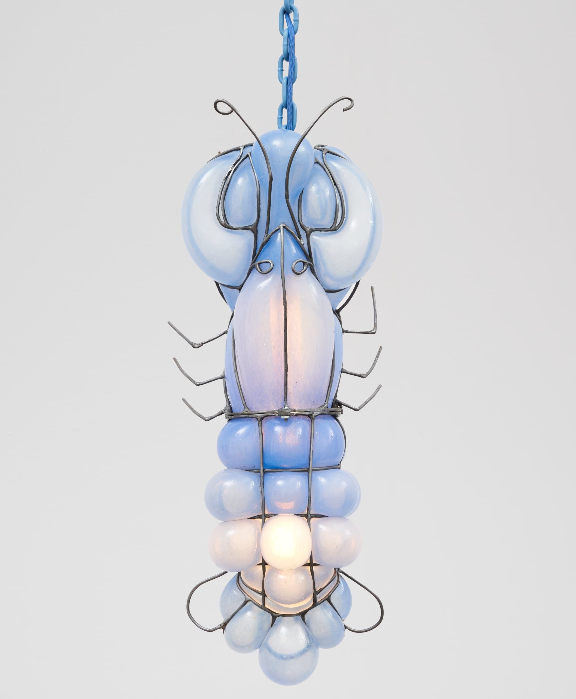 a glass blown pendant lamp hanging from a chain that bubbles inside steel armature and appears like a blue lobster