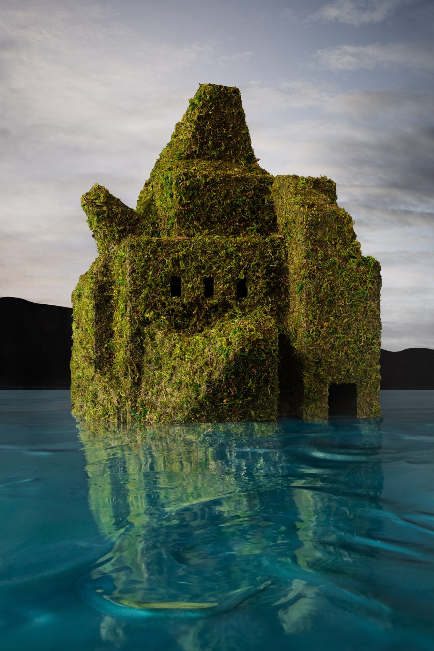 water rises around a moss enveloped architectural model