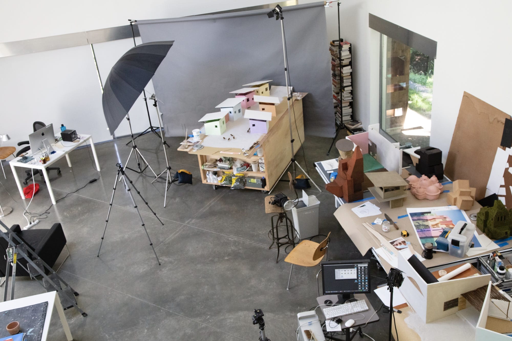an aerial view of the artist's studio with architectural models on a table and photo equipment