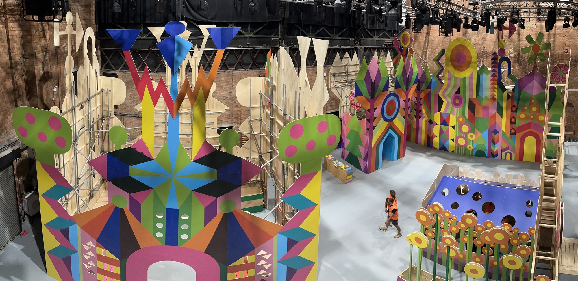 construction underway of a large-scale installation with painted panels and colorful geometry