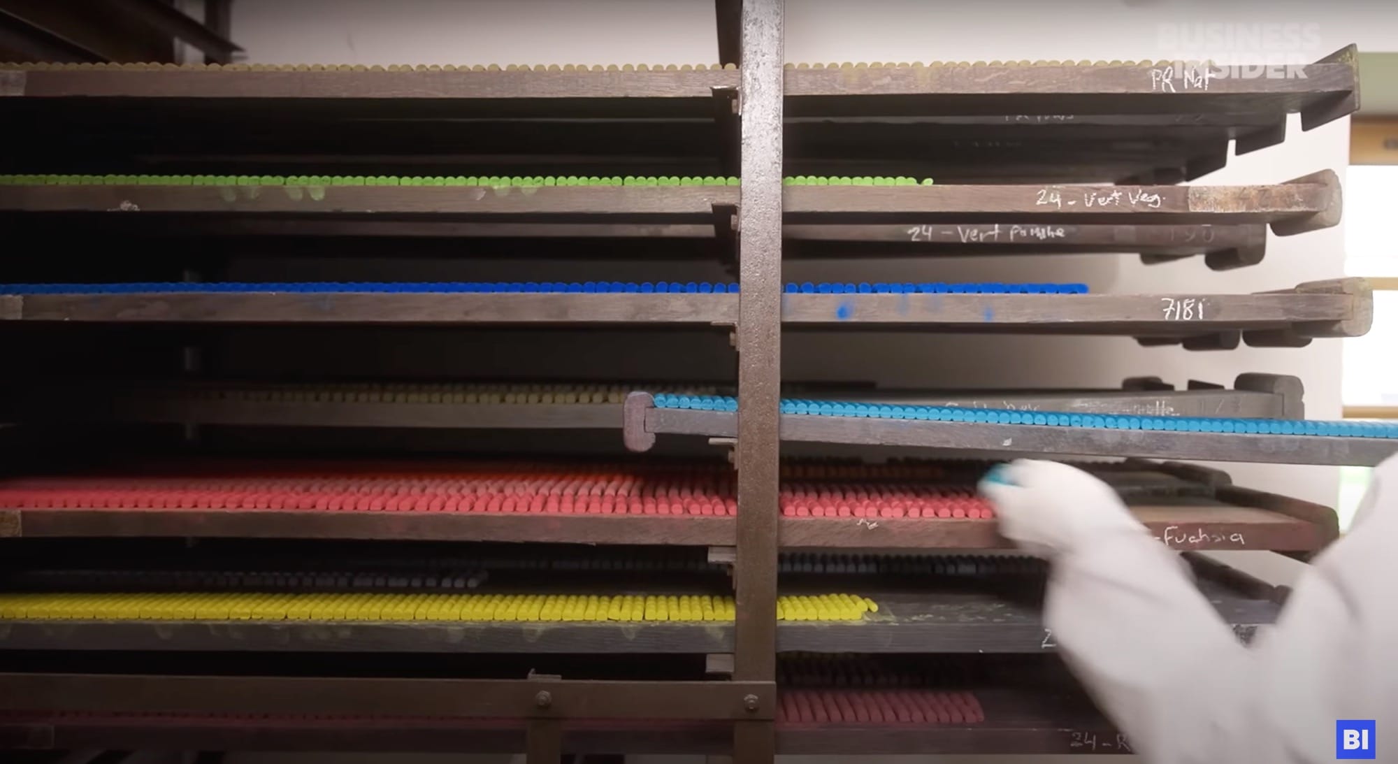 a still from a short documentary about a pastel maker in France, showing a trays of pastels being loaded onto a shelving unit to cure or dry