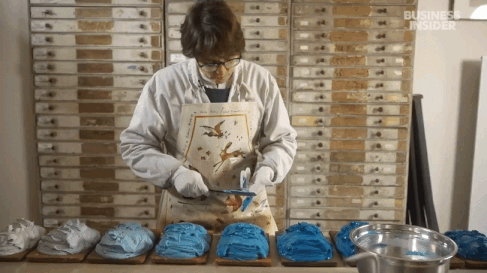 a gif from a short documentary about a pastel maker in France, showing different colors of blue pigment being scraped into piles on a worktable in preparation for turning them into pastel sticks