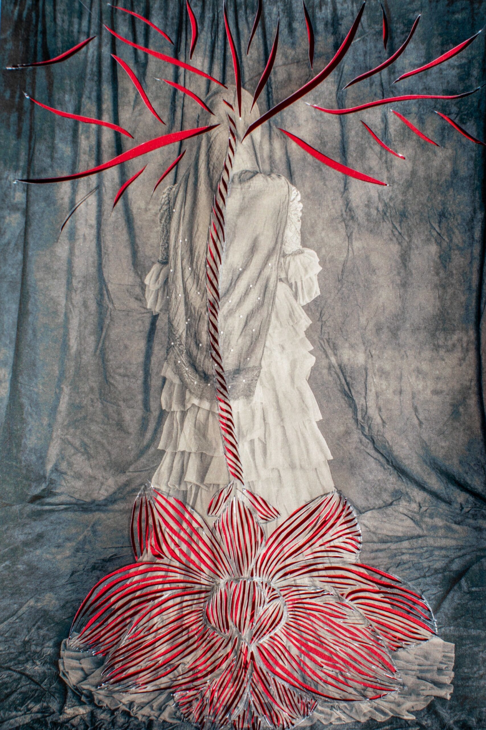 a black-and-white photograph of an anonymous south Asian woman that has been cut into patterns with the outline of an upside-down flower, with red paper shows through from the back