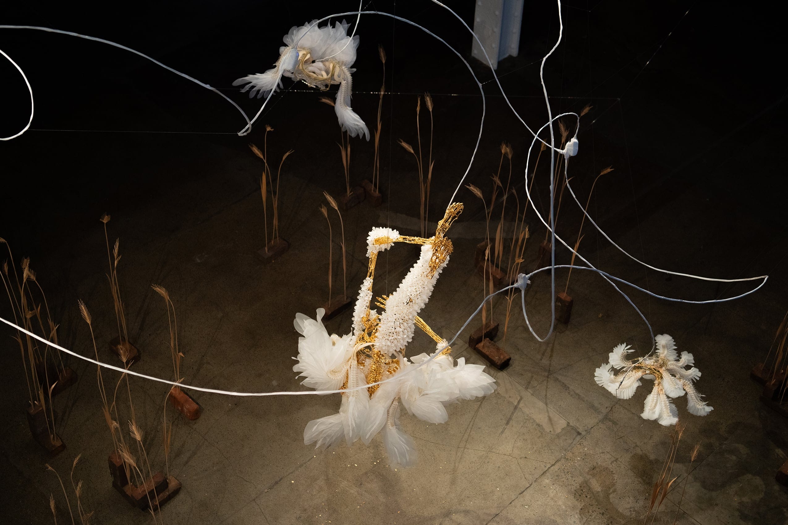 an aerial view of three suspended white and gold sculptures
