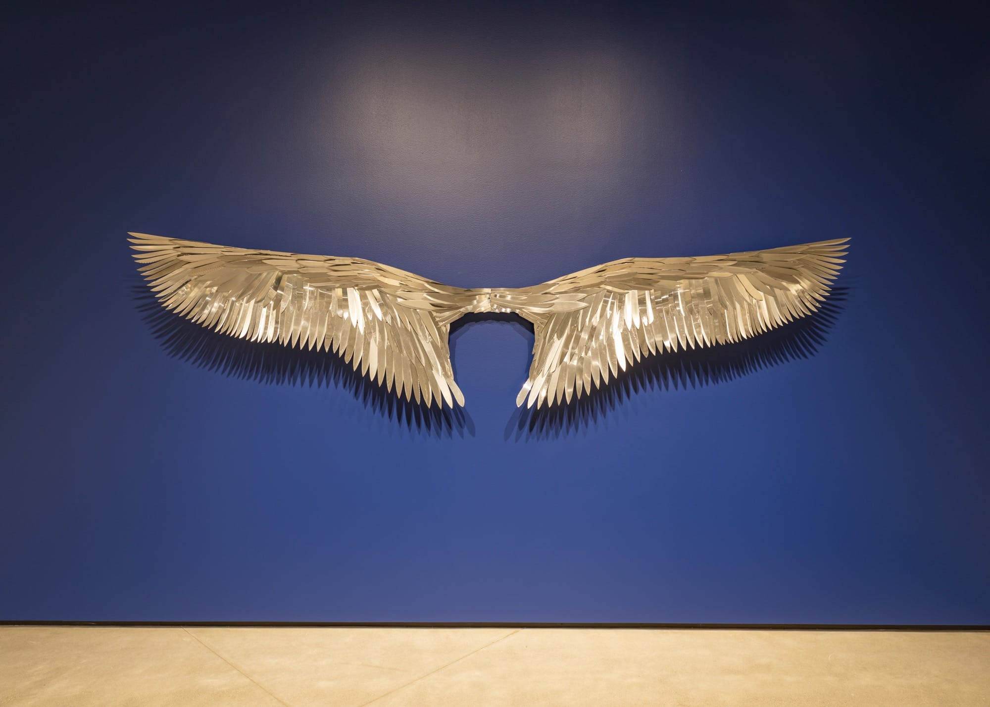 a wall sculpture of a bird's wingspan made from repurposed knives