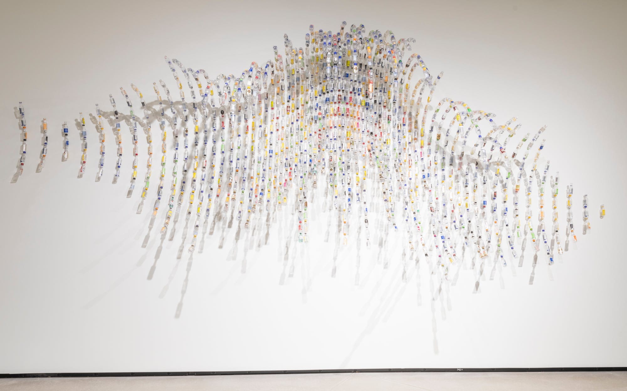 a wall sculpture that resembles the rhythms of a starling murmuration, made from tiny liquor bottles